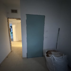 חדר עם דלת ירוקה ושק בנייה