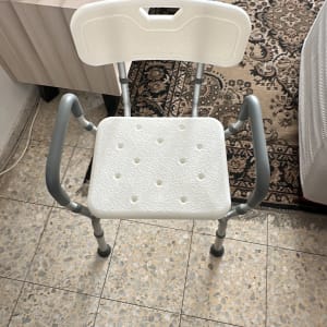 כיסא פלסטיק עם ידיות מתכת על רצפה מרוצפת