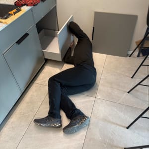 אדם מתקן ארון מטבח עם כלים על השיש