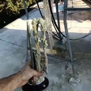 יד מחזיקה חוטי חשמל עם בידוד פגום ליד מיכל גדול