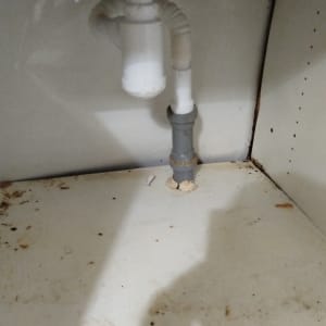 צנרת מתחת לכיור עם סימני חלודה ולכלוך