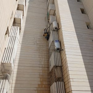 אדם תלוי על חבל ליד דודי שמש על קיר בניין