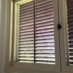 תריסים חומים על חלון עם מסגרת עץ