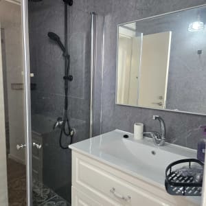 מקלחת עם ראש מקלחת שחור ודלת זכוכית