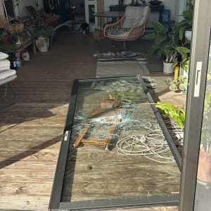 דלת זכוכית שבורה עם מסגרת אלומיניום על רצפת עץ