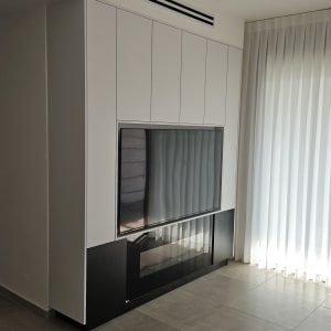 טלוויזיה מותקנת בארון עץ לבן עם דלתות