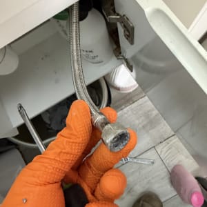 תיקון צינור מתחת לכיור עם כפפות כתומות