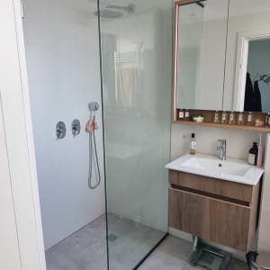 מקלחון זכוכית בחדר אמבטיה מודרני עם כיור ומראה