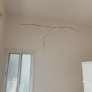 קיר עם סדקים בחדר עם חלון ומנורה