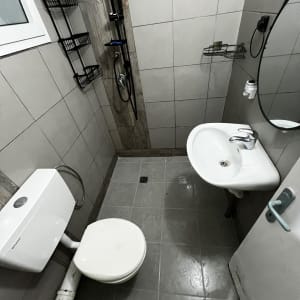 חדר אמבטיה עם אריחים חדשים, מקלחון וכיור מותקן.