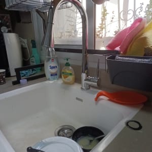 כיור מטבח עם כלים וסבון ליד ברז נירוסטה