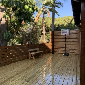 דק עץ עם ספסל וסל כדורסל בחצר