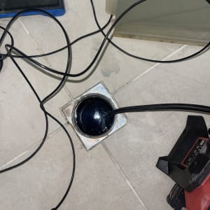 כבל שחור נכנס לניקוז ברצפה