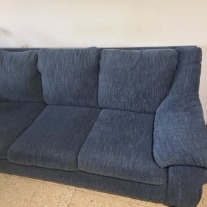 ספה כחולה בחדר עם קיר לבן