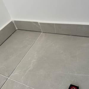 ריצוף קרמיקה בפינת חדר עם כלי מדידה קטן.