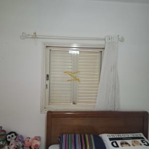 חלון עם תריסים סגורים ומיטה עם כריות צבעוניות