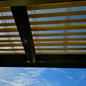 קורות עץ עם כיסוי פלסטיק שקוף בגינה