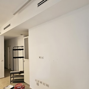 דלי צבע ומברשת על רצפה ליד קיר לבן