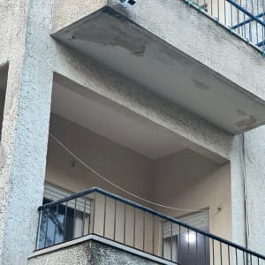 מרפסת עם מעקה מתכת ומצלמת אבטחה מותקנת