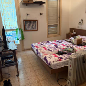 חדר שינה עם מיטה, רדיאטור ומוצרים על המיטה