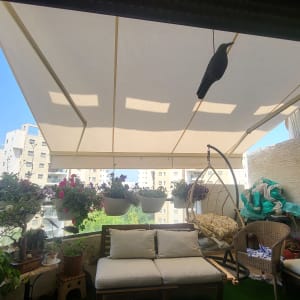 סוכך לבן גדול מעל מרפסת עם צמחים תלויים