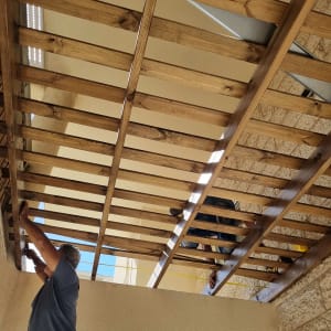 שני אנשים מתקינים פרגולה מעץ בגינה