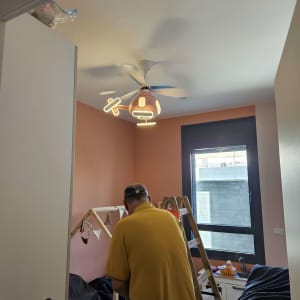 חשמלאי עובד על חיווט ליד סולם בחדר