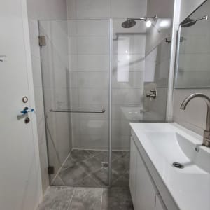 מקלחון זכוכית עם ראש מקלחת עגול וקיר אריחים