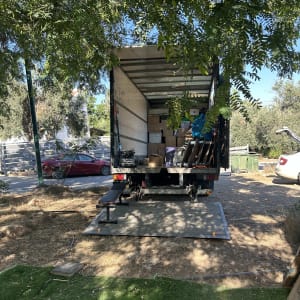 משאית הובלה עמוסה בארגזים וציוד דירה עם רמפה הידראולית פתוחה