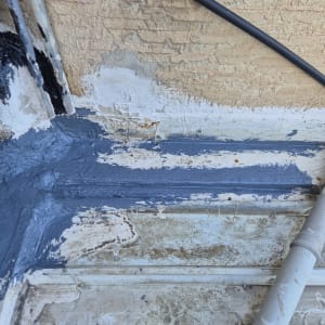 איטום קיר עם חומר אפור ליד צינור פלסטיק