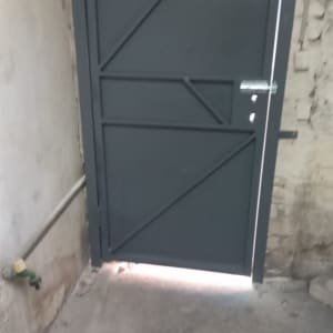 דלת מתכת אפורה עם קיר לבנים ברקע