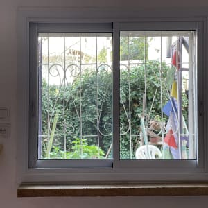 חלון אלומיניום עם מסגרת לבנה וברזל דקורטיבי