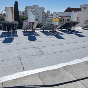 גג אטום עם שכבת איטום לבנה מסביב לדודים