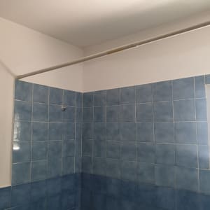 קיר צבוע בלבן מעל אריחים כחולים בחדר אמבטיה