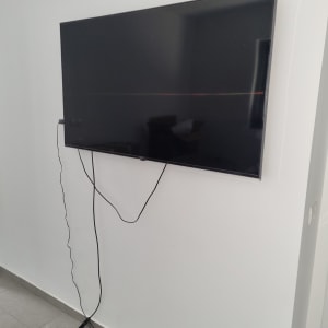 טלוויזיה מותקנת על קיר עם כבלים תלויים