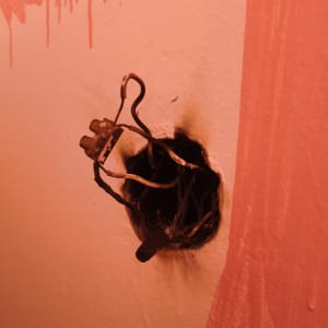 חוטי חשמל חשופים בקיר עם סימני שריפה