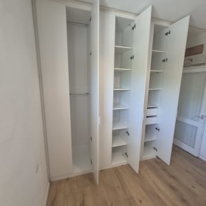 ארון בגדים לבן עם דלתות פתוחות בחדר