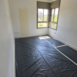 חדר עם יריעות פלסטיק על הרצפה לקראת צביעה