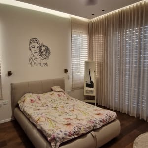 וילונות בהירים על חלונות גדולים בחדר שינה