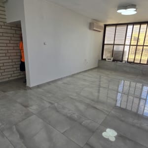 חדר ריק עם קירות לבנים ורצפת שיש אפורה