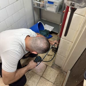 אדם משתמש במקדחה לתיקון צנרת בקיר