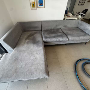 ספה אפורה עם כתמים וכלי ניקוי על הרצפה