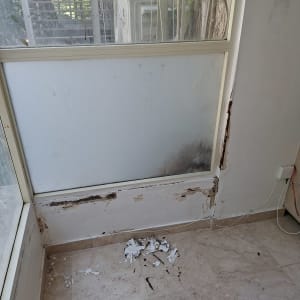 קיר עם נזקי רטיבות וכתמים ליד חלון