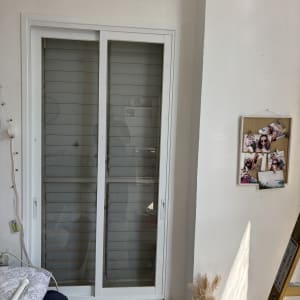 חלון זכוכית עם תריסים, סולם ותמונות על הקיר