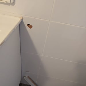 קיר עם חור קטן ואריחים לבנים