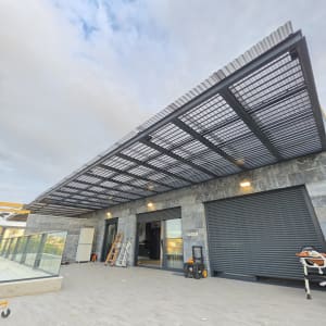 פרגולת אלומיניום כהה עם קירוי סנטף במרפסת בית