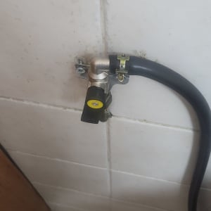 שסתום גז מחובר לצינור שחור על קיר לבן