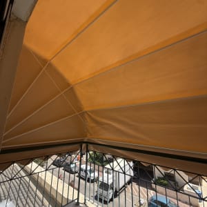 סוכך כתום מותקן מעל מרפסת עם נוף לרחוב