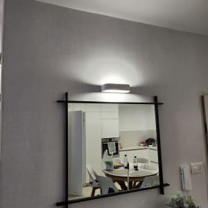 מראה עם מסגרת שחורה על קיר עם מנורה מעל