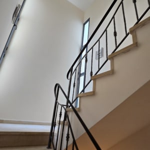 מדרגות עם מעקה מתכת וקיר צבוע בלבן